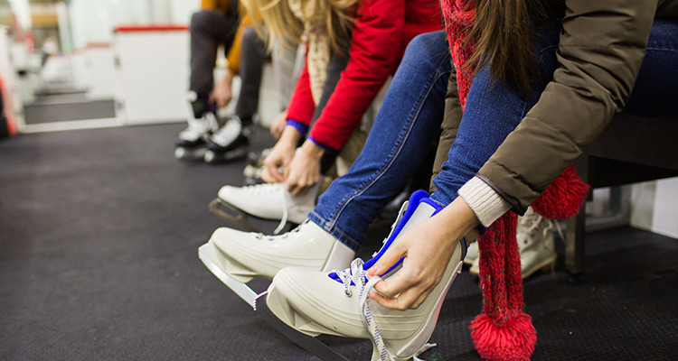 Women lacing skates up - how to reduce ice rink heating